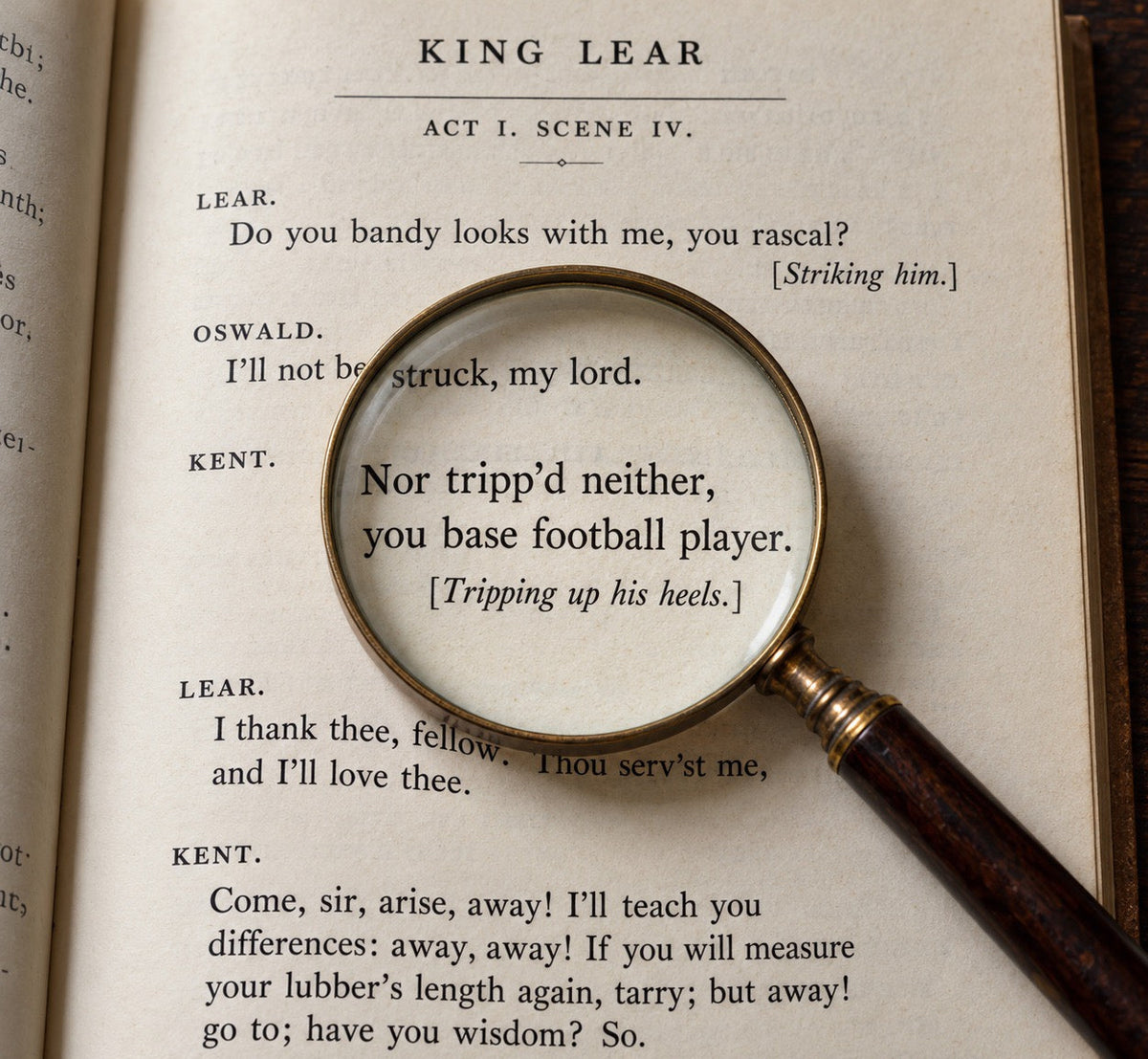 A vintage-style magnifying glass with a dark wooden handle and gold-toned rim rests on an open book page showing Shakespeare's King Lear text. The magnifying glass is focused on a line of dialogue, with the surrounding book pages and a dark wood surface visible.
